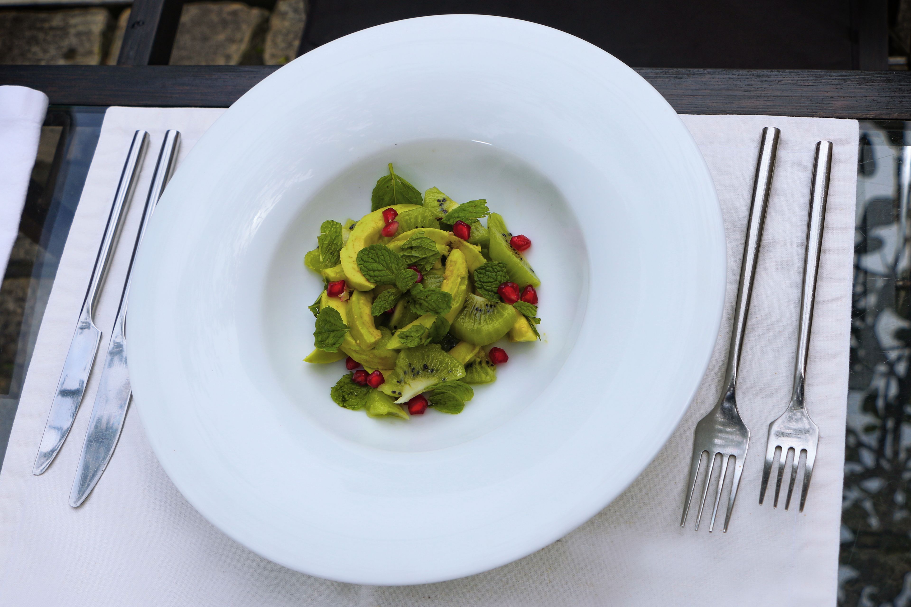 A white plate with a fruit salad on a table.