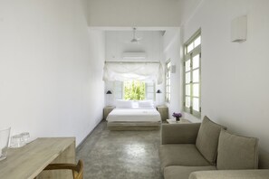 Un dormitorio con cama, sofá, mesa y ventana.