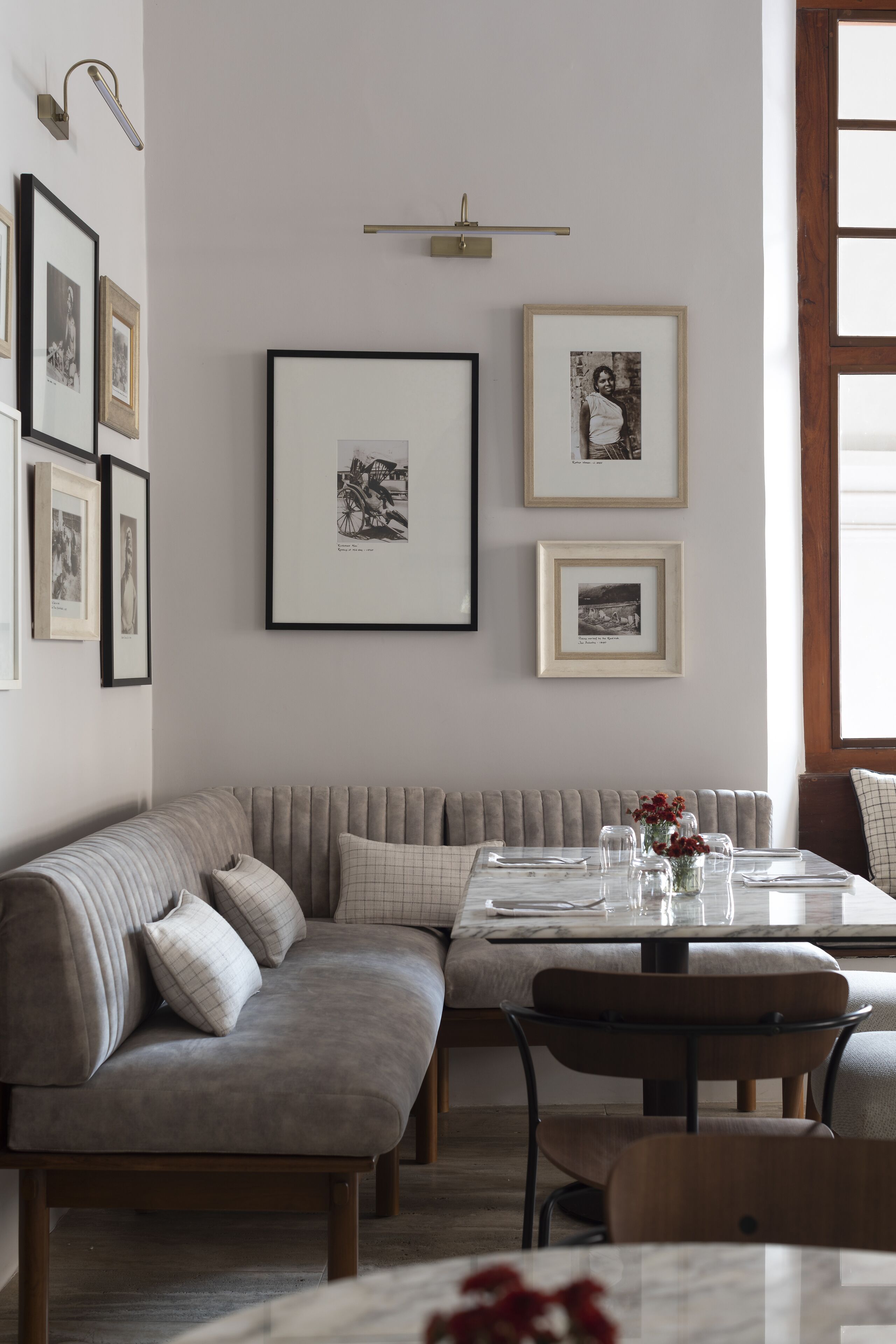 A dining area with a cushioned bench, a table set for two, and framed pictures on the wall.