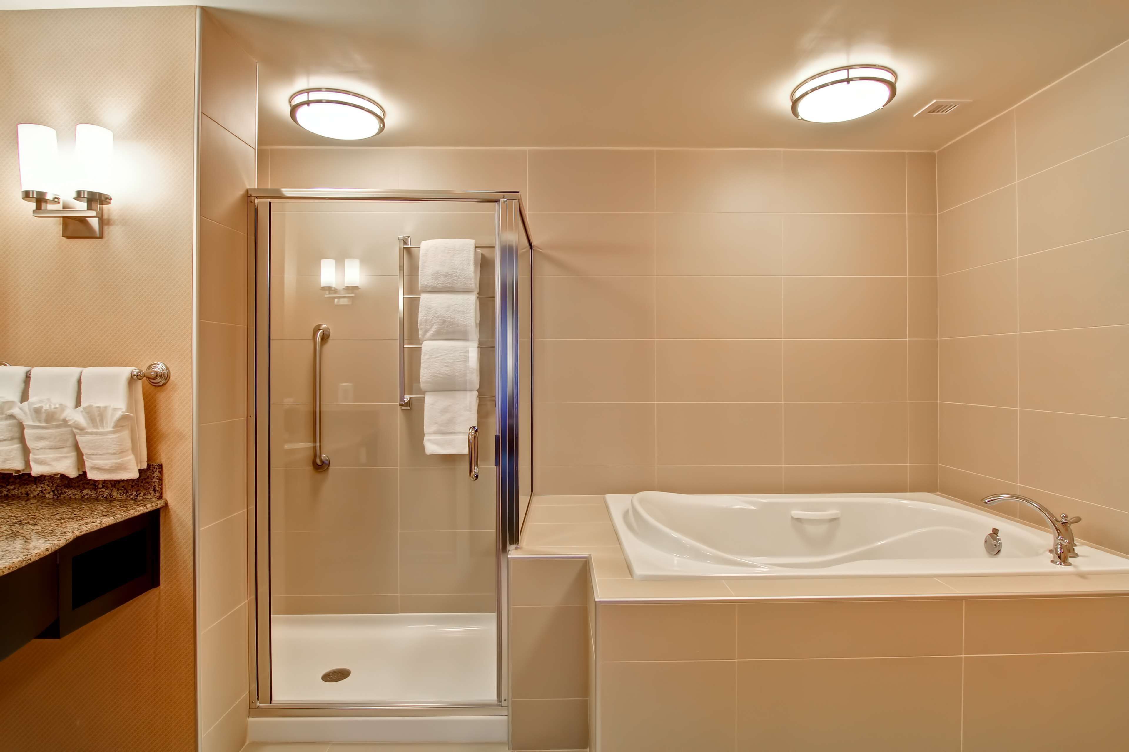 Un bagno moderno con doccia vetrata, vasca freestanding e vanità con piano.