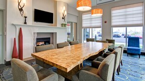 A conference room with a large wooden table, comfortable chairs, a fireplace, and large windows with blinds. - Hilton Garden Inn Woodbridge (Woodbridge)