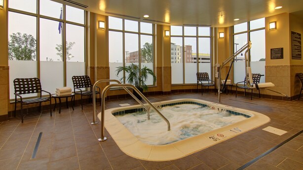 A large indoor pool with a hot tub, surrounded by chairs and a staircase. - Hilton Garden Inn Woodbridge (Woodbridge)