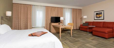 Een hotelkamer met een bed, bureau, televisie en rode bank.