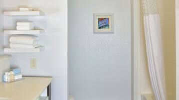 Un baño con piso de madera, lavamanos blanco, toallero y cortina de ducha.