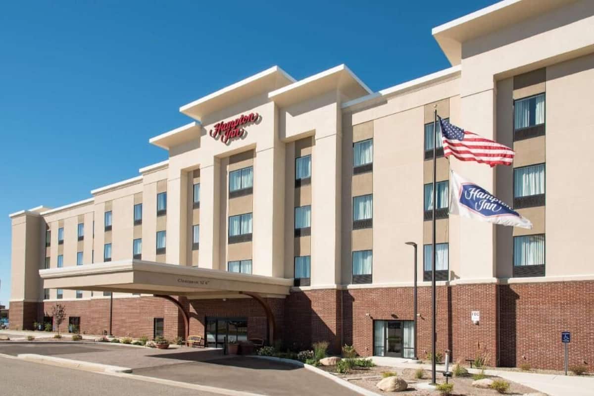 A Hampton Inn hotel with a brick facade, multiple windows, and an American flag.