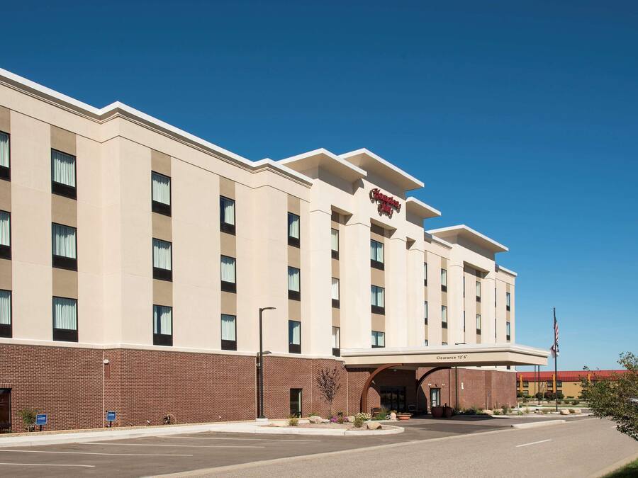 Un hotel grande y moderno con una entrada destacada y un cielo despejado.