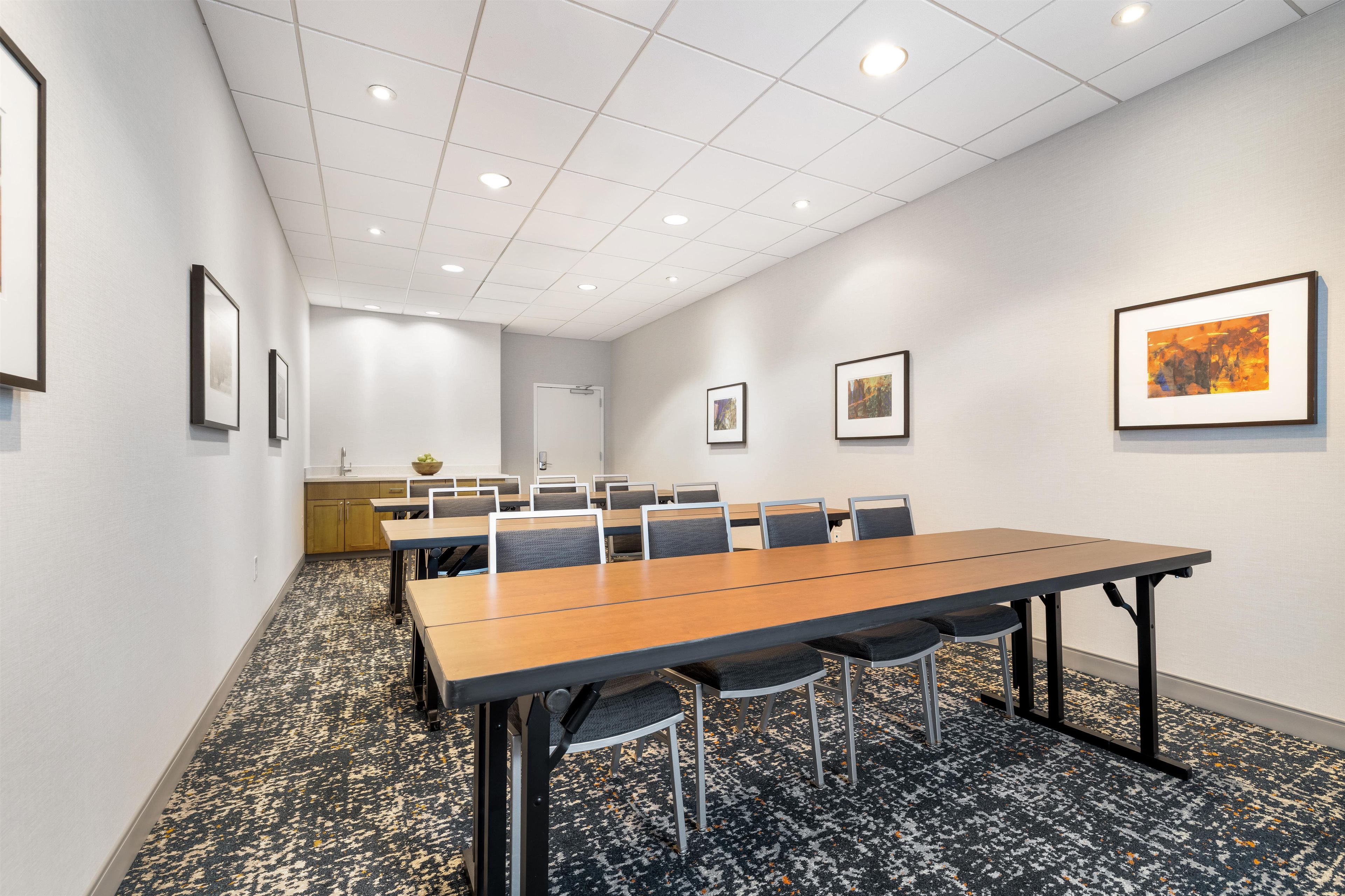 A conference room with a long table, chairs, and framed artwork on the walls.