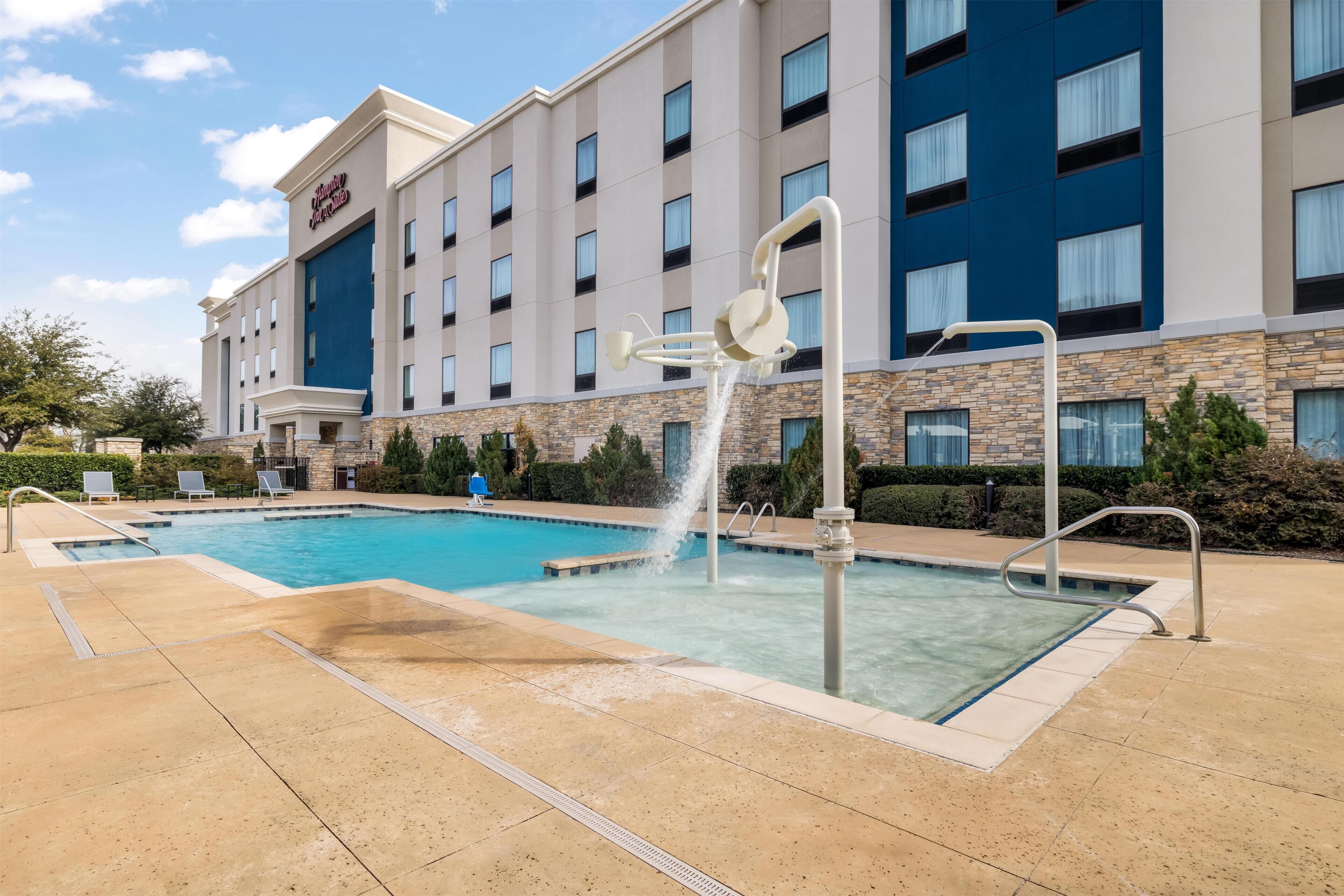 A hotel with a swimming pool, a water feature, and a stone facade.