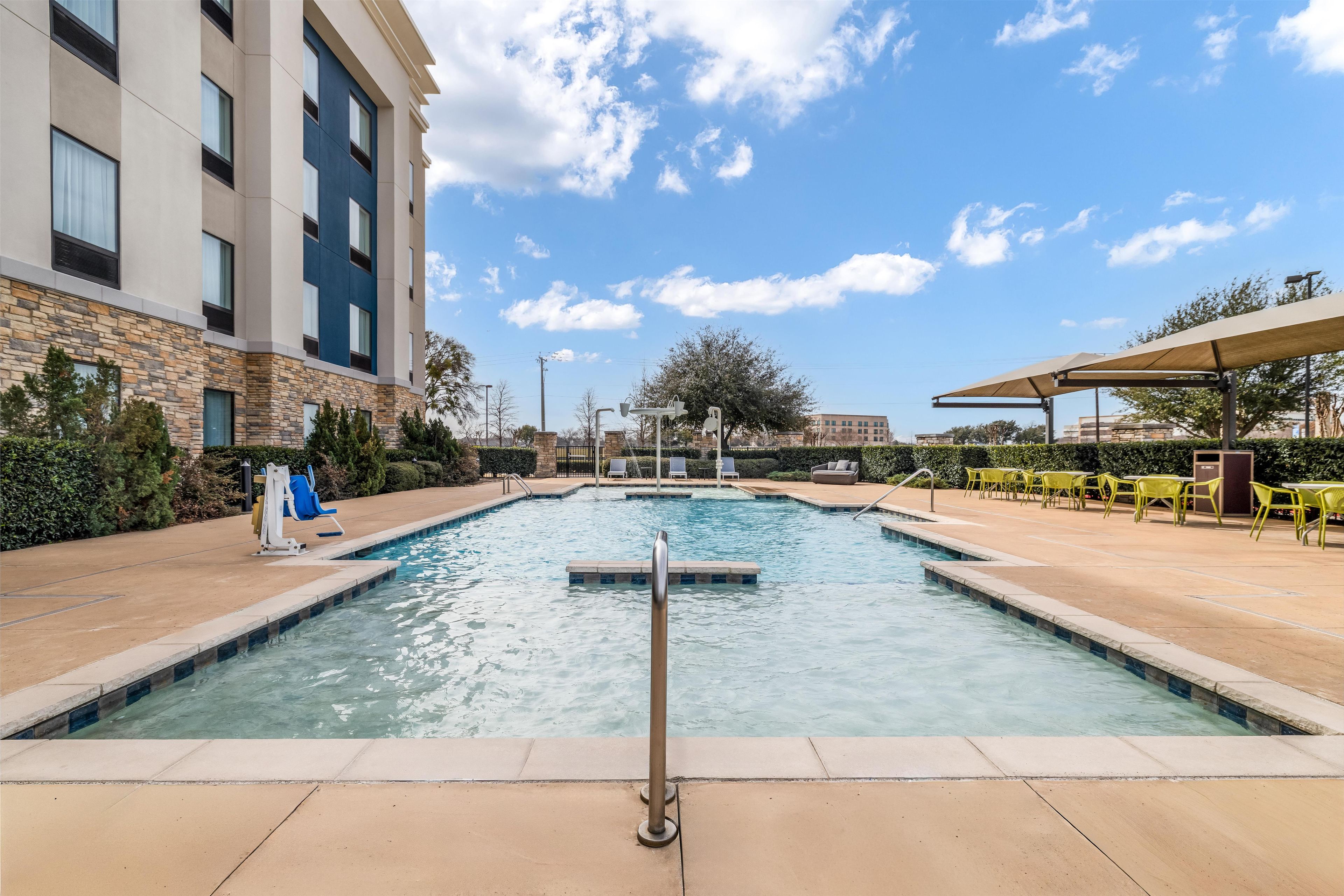 A swimming pool with a lifeguard chair, lounge chairs, and a covered seating area.