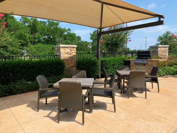 An outdoor patio area with a covered seating arrangement, stone pillars, and a grill. - Hampton Inn & Suites Dallas/Plano-East (Plano)