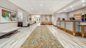 A hotel reception area with a reception desk, seating area, and a patterned carpet. - Hampton Inn & Suites Dallas/Plano-East (Plano)