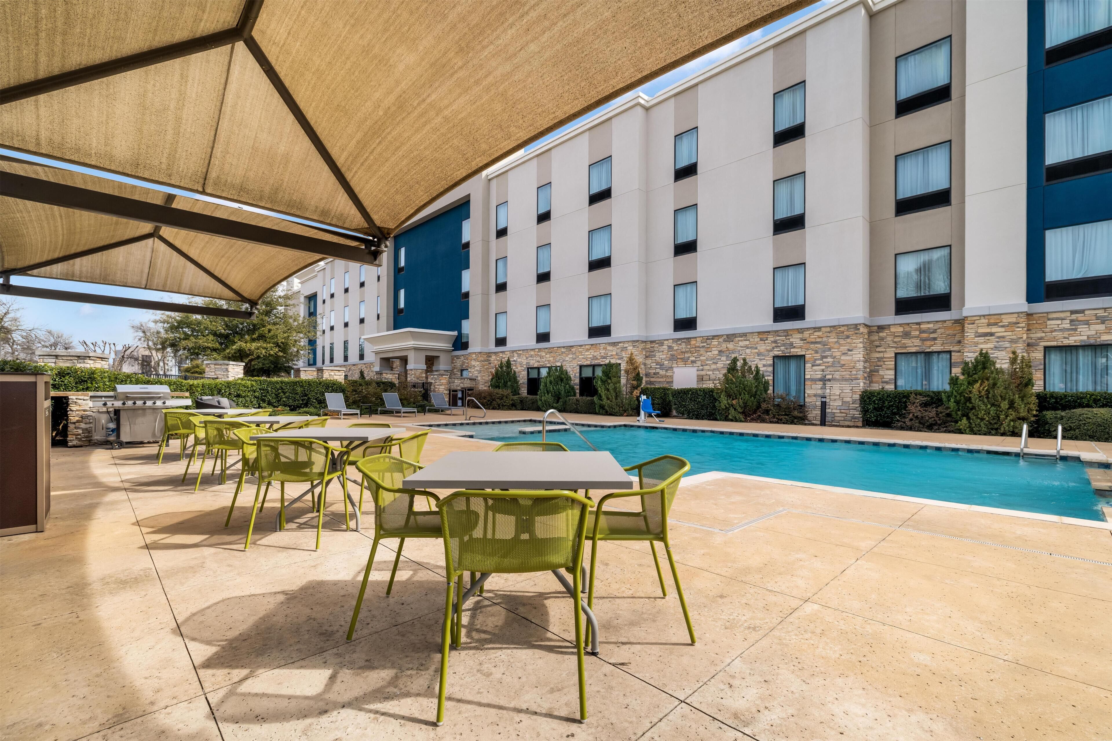 A hotel pool area with outdoor seating and a covered patio.