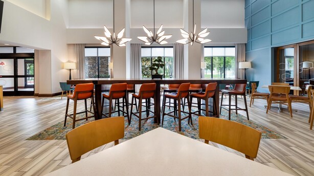 A modern hotel lobby with a bar area, seating arrangements, and large windows. - Hampton Inn & Suites Dallas/Plano-East (Plano)