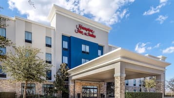 A Hampton Inn & Suites hotel with a modern facade, large windows, and a welcoming entrance.
