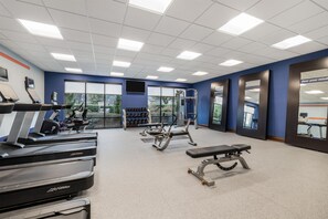 Un gimnasio con cintas de correr, máquinas de pesas y mancuernas.