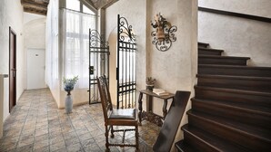 A hallway with a wooden chair, a vase with flowers, a table with a book, and a staircase. - Boutique Residence by Little King (Prague)