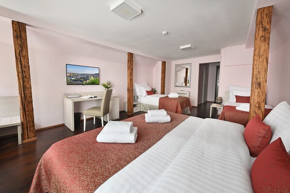 A hotel room with a large bed, a desk, a chair, a small table, and a mirror.