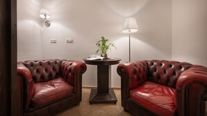 A room with two leather armchairs, a round table with a plant, and two wall-mounted lamps. - Boutique Residence by Little King (Prague)