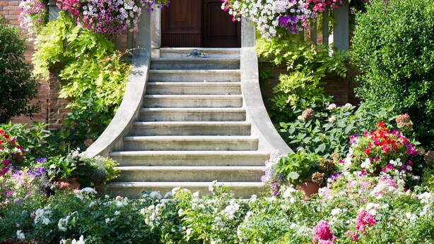 A brick building with a wooden front door, a set of stone steps leading up to the entrance, and a balcony with flower boxes. - Villa Ines (Venice)