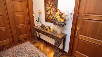 Un couloir en bois avec un banc, un vase de fleurs et un tableau accroché au mur.