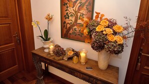 A wooden console table with a framed artwork, a vase of yellow roses, and candles. - Villa Ines (Venice)