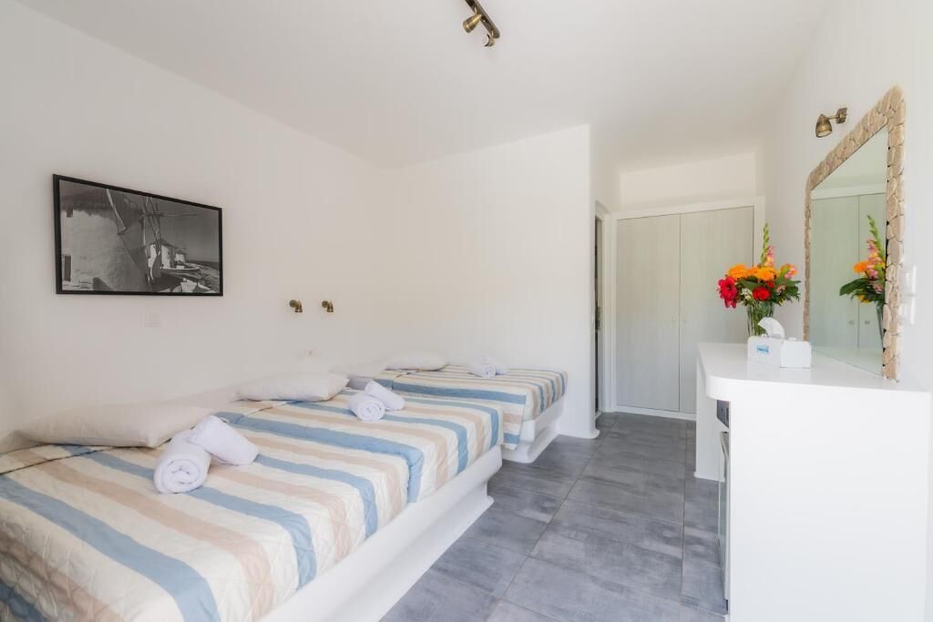 A hotel room with two beds, a white desk, a mirror, and a framed picture on the wall.