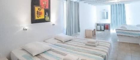 Habitación de hotel con dos camas, un escritorio, una silla y un baño al fondo.