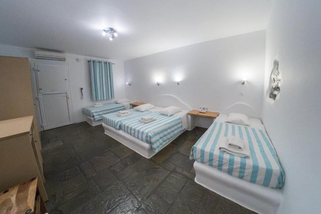 A hotel room with two beds, a wooden nightstand, a desk, and a wardrobe.