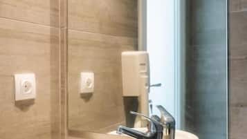 A modern bathroom with a round sink, a mirror, and a window.