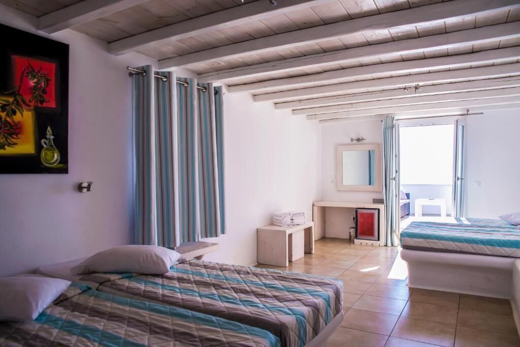 A hotel room with two beds, a desk, a mirror, and a bathroom visible through an open door.