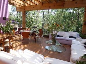 Une terrasse extérieure avec une table à manger, des chaises, un canapé et une table basse en verre.