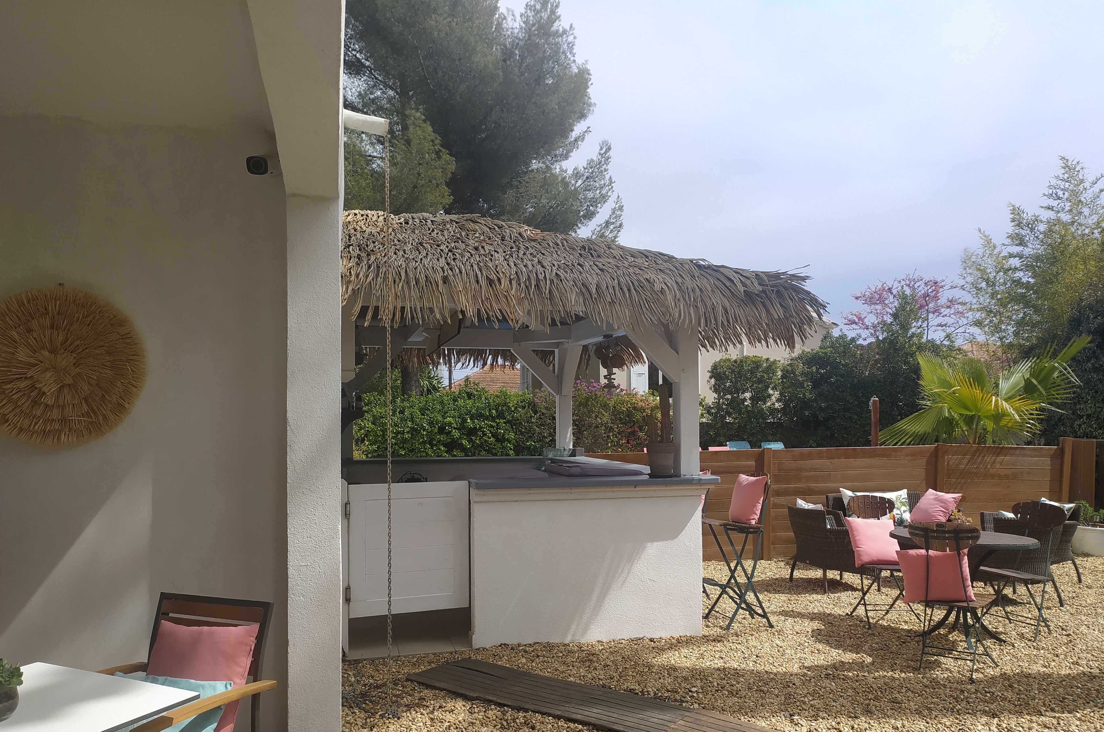 An outdoor patio with a thatched roof structure, seating area, and a small bar counter.