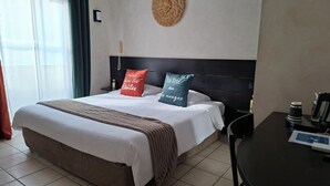 A hotel room with a bed, a bedside table with a coffee maker, and a wall-mounted decorative item. - Hôtel Synaya (Sanary-sur-Mer)