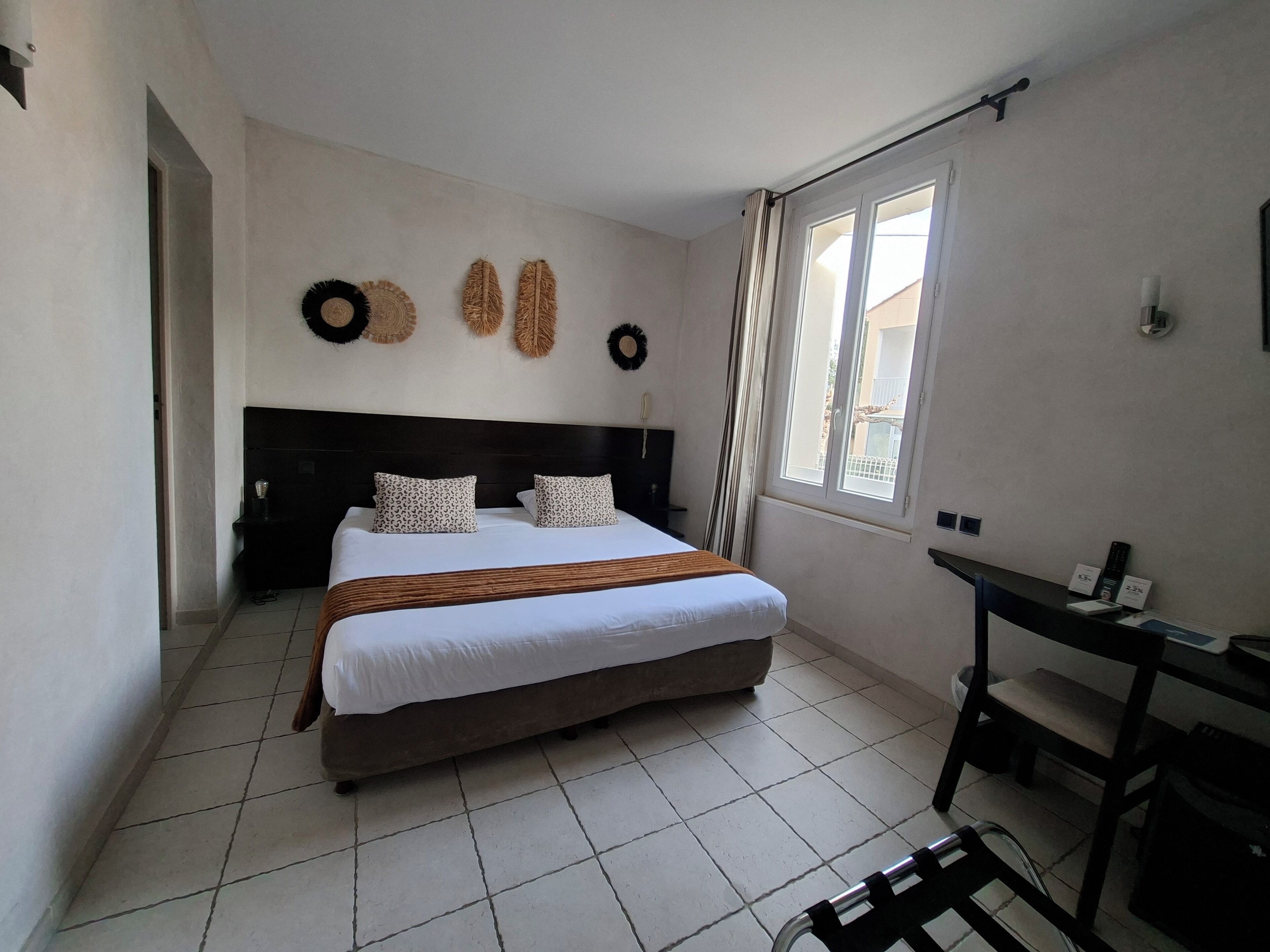 Ein Hotelzimmer mit einem großen Bett, einem Schreibtisch und einem Vorhangfenster.