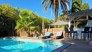 A swimming pool with lounge chairs and a shaded area. - Hôtel Synaya (Sanary-sur-Mer)