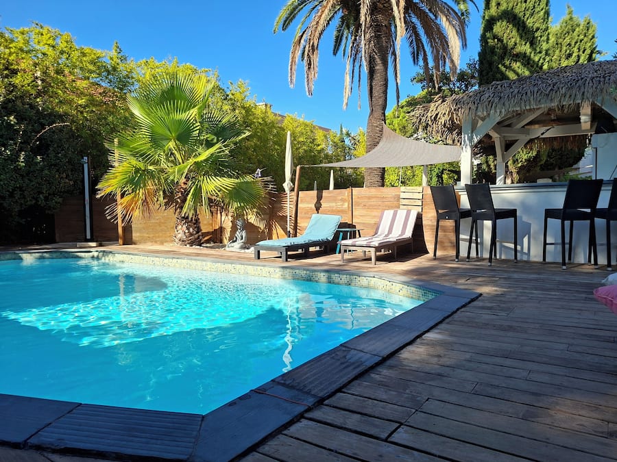 A swimming pool with lounge chairs and a shaded area.