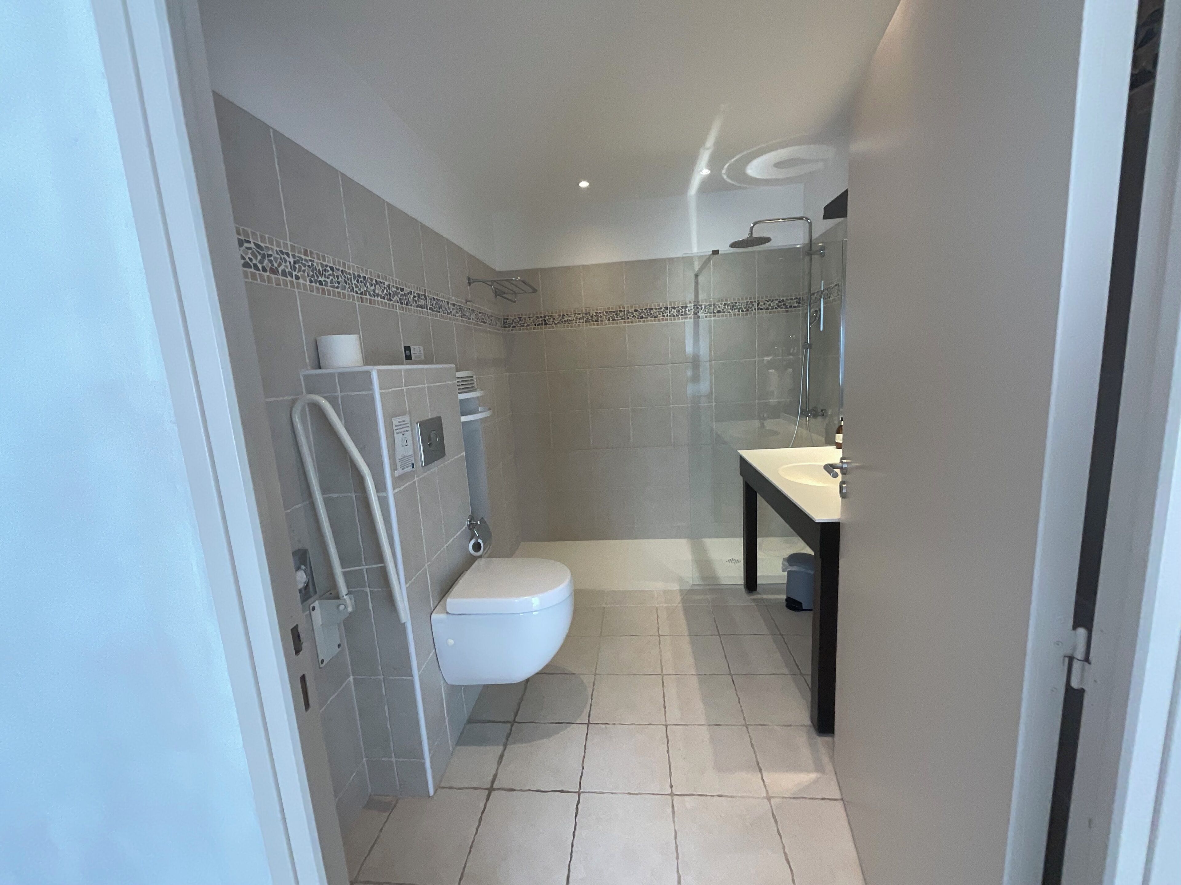 A modern bathroom with a toilet, shower, and sink.