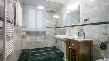 A modern bathroom with a marble shower, a sink with a mirror, and a wooden vanity.