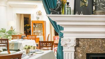 A dining room with a fireplace, a table set for a meal, and a view of the city through a window.