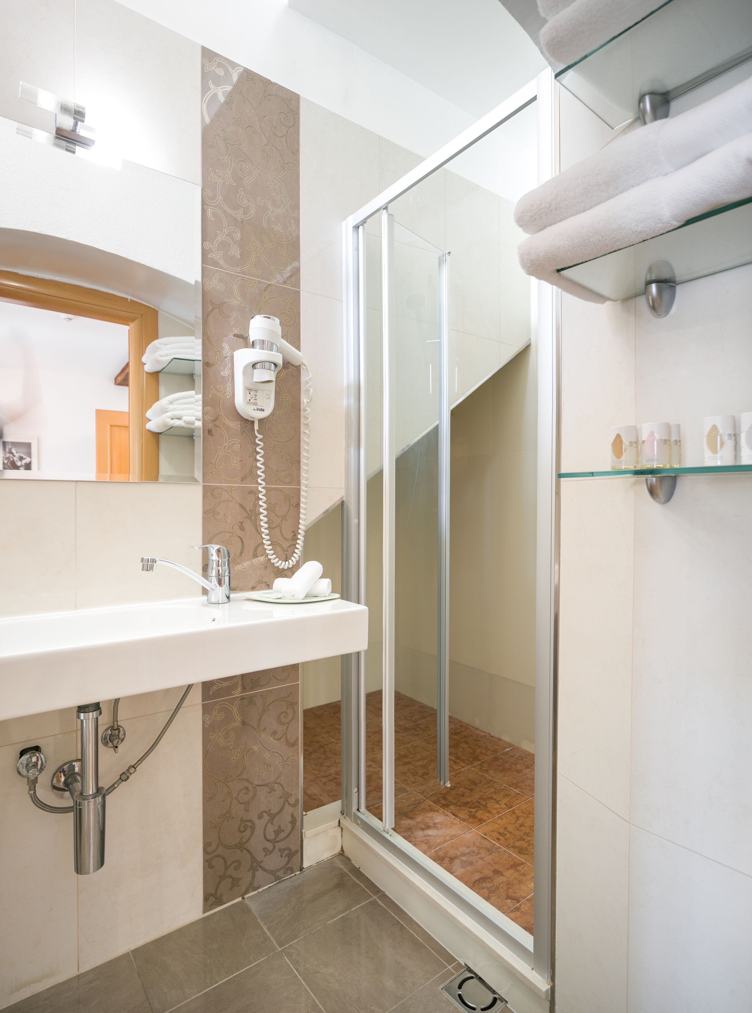 A modern bathroom with a glass shower enclosure, a vanity with a sink, and a towel rack.