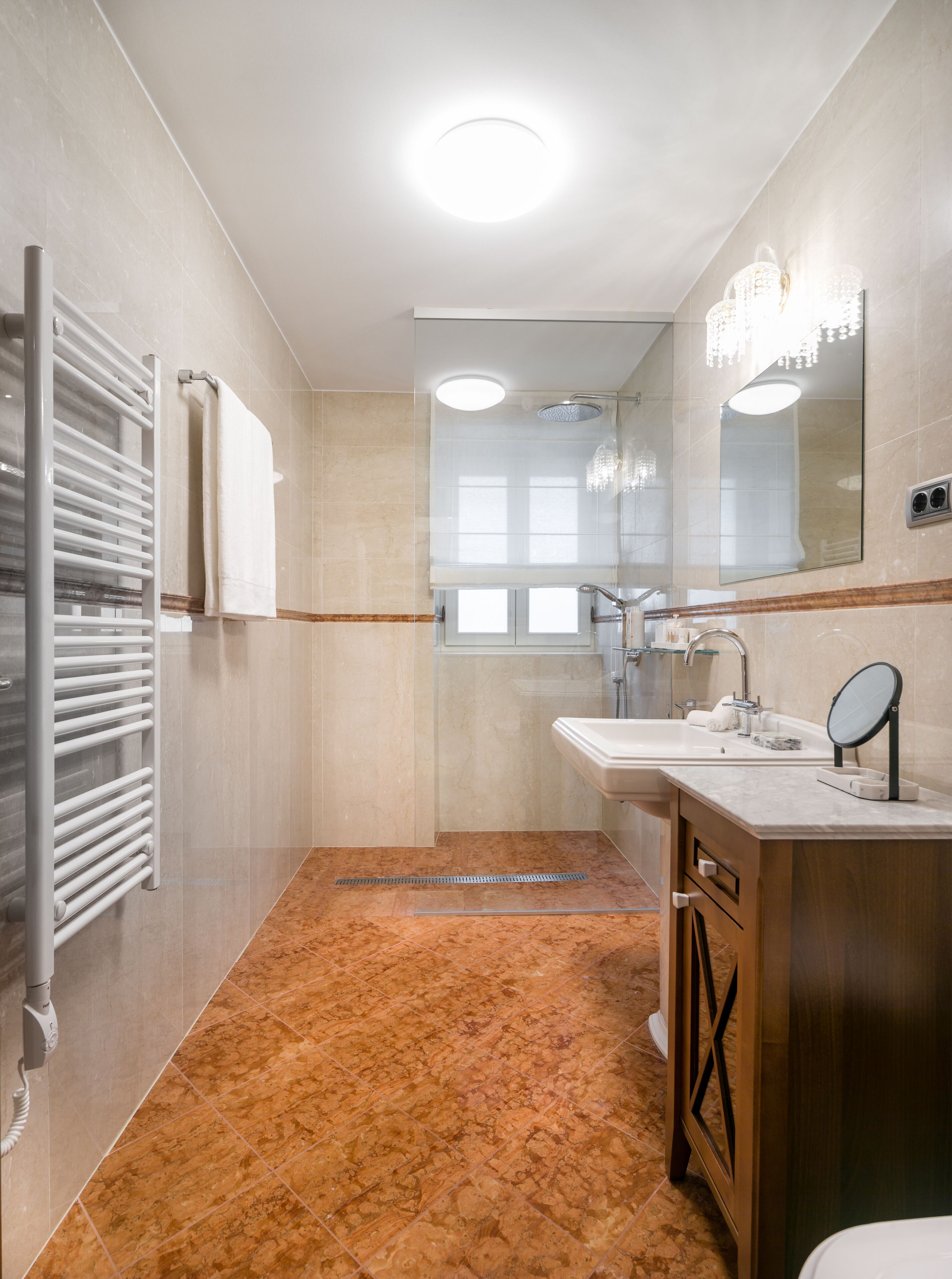 A modern bathroom with a shower, two sinks, a vanity with a mirror, and a towel rack.