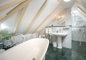 Une salle de bain moderne avec une baignoire sur pieds, un lavabo sur colonne et une douche à parois de verre.