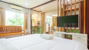 A hotel room with a large bed, a flat-screen TV, a wooden bench, a desk, and a view of the outdoors. - Kamala Beach Residence (Kamala)