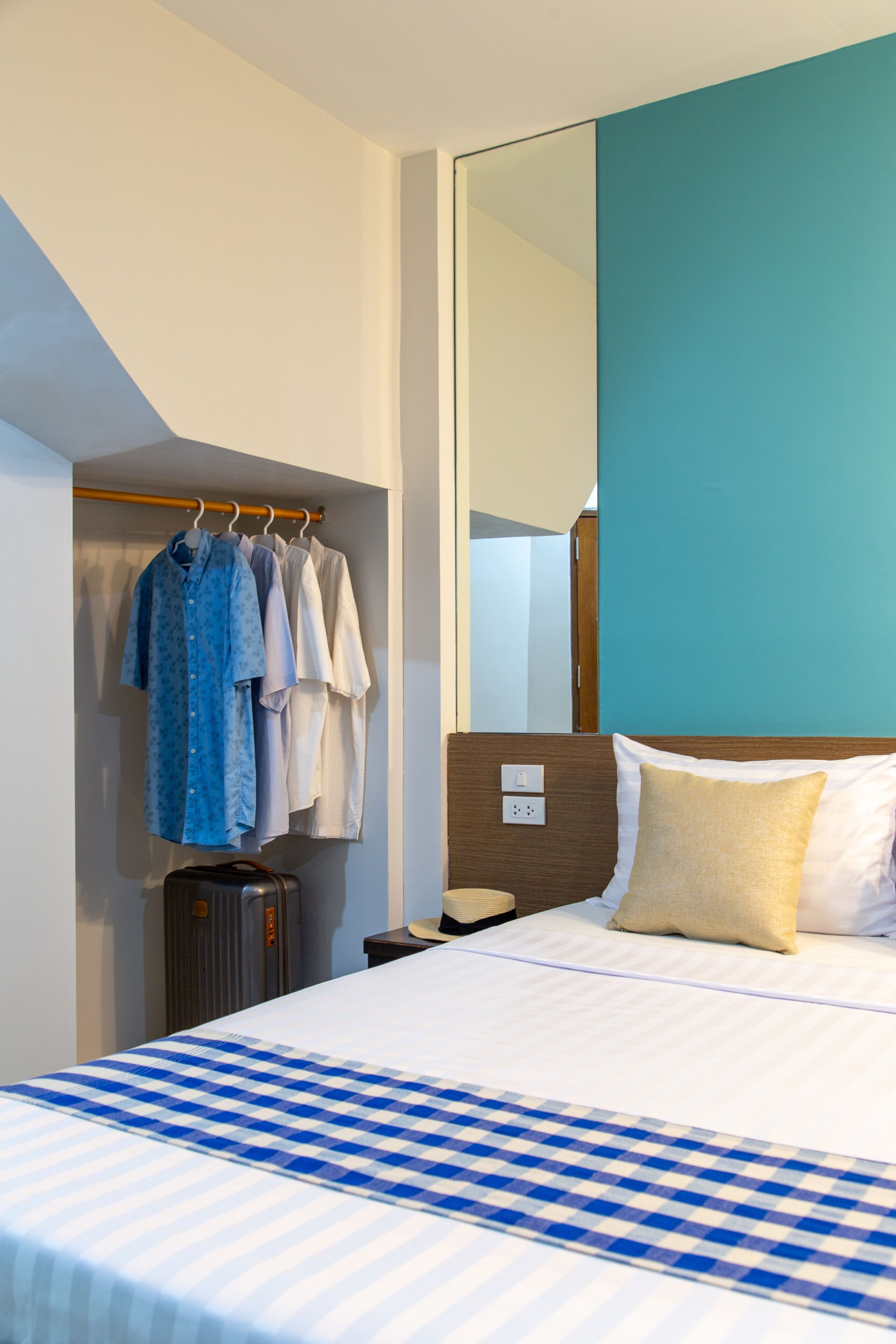 A hotel room with a bed, a wardrobe, and a mirror.