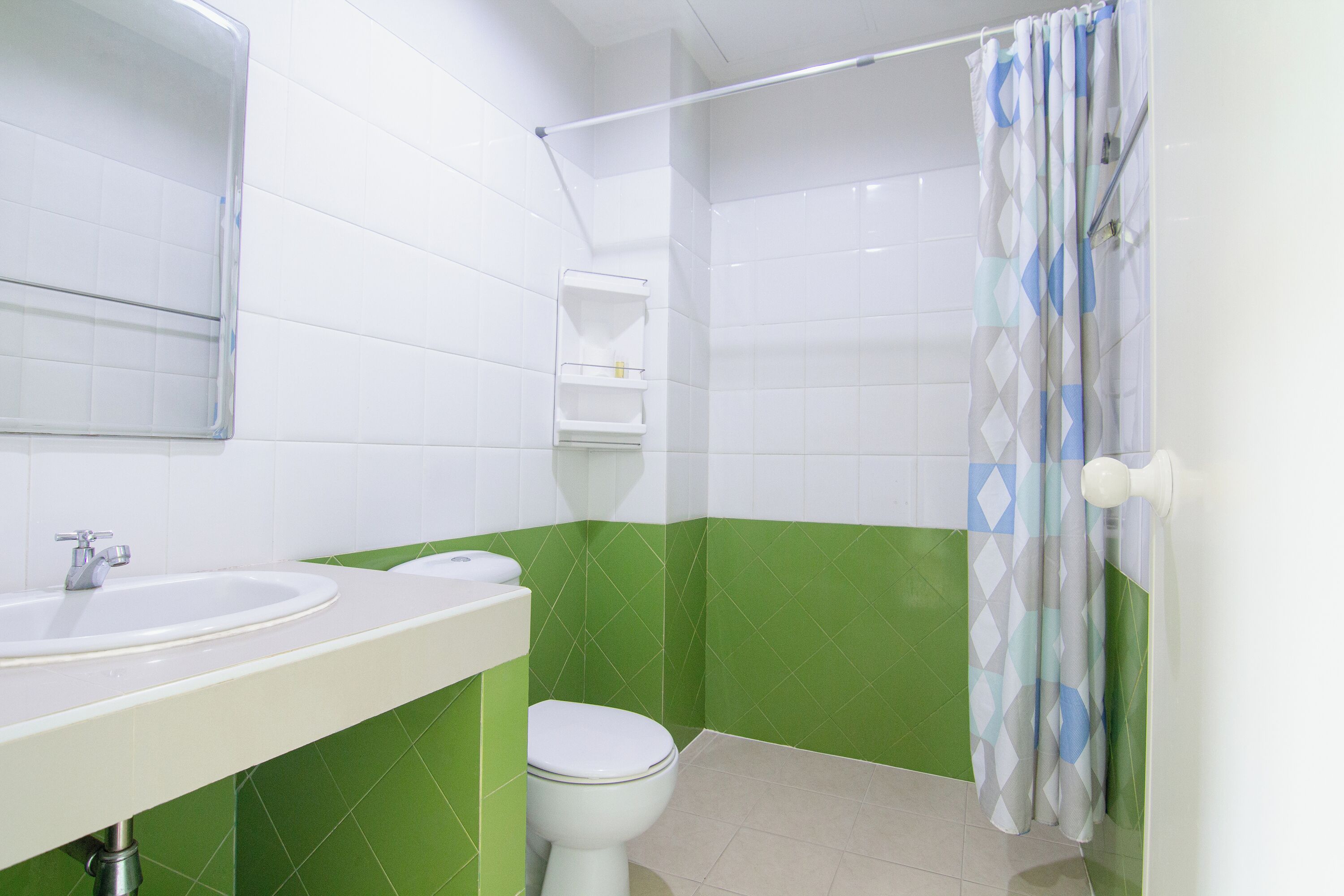 Une salle de bain avec un lavabo blanc, des toilettes et un rideau de douche.