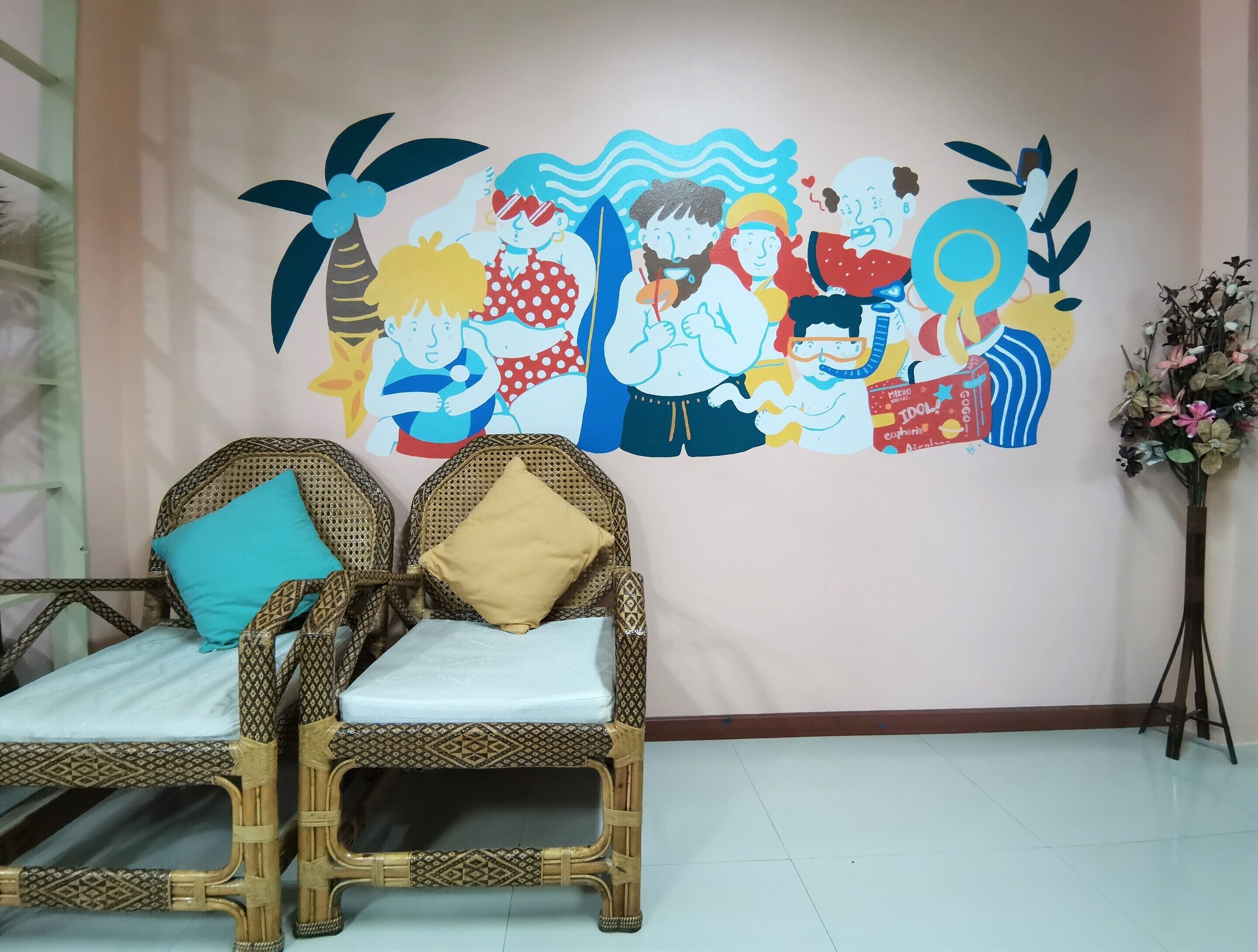 A room with two wicker chairs, a small table, and a wall mural depicting various characters.