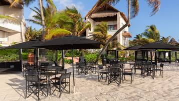 Relax in a beachside setting with comfortable seating under shaded umbrellas.