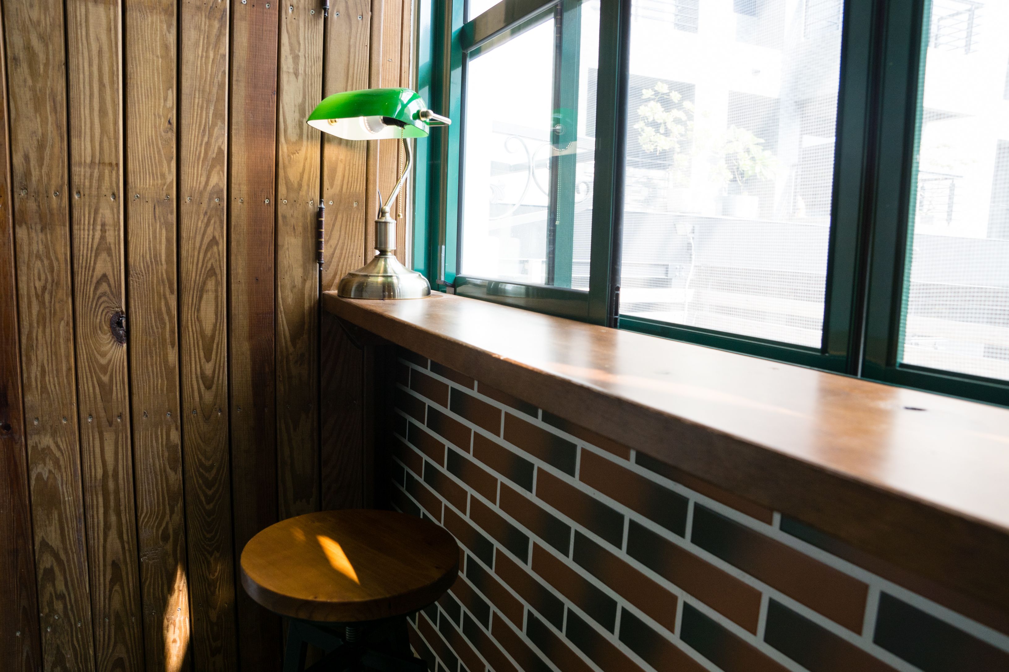 A corner with a wooden wall, a brick wall, and a window with a view of buildings outside.