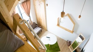 A modern room with a wooden ceiling, a white sofa, a small round table, and hanging pendant lights. - Hinoki Mansion (Tainan)