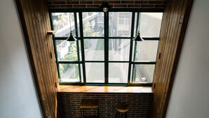 A corner room with a large window, two wooden chairs, and a bench. - Hinoki Mansion (Tainan)